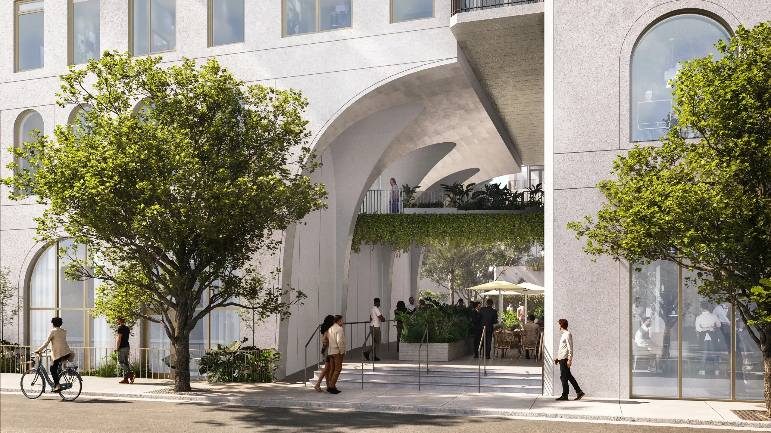 Modern building entrance with curved architecture, large windows, and landscaped trees in courtyard.